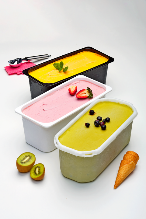 Three ice cream 5L containers with different flavours of ice cream, surrounded by fruits on a white background.