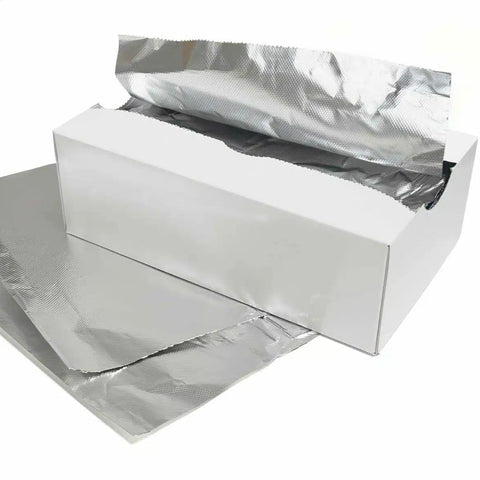 White cardboard box with sheets of aluminium foil on a white background