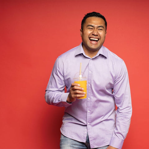 Picture of a Bonson employee laughing holding a Bonson cup filled with orange juice, on a red background