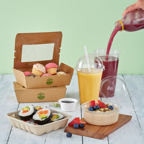 Assorted food items including sushi, smoothies, and pastries on a wooden table with a green background.