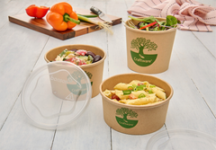 Three paper Craftware™ containers of differing sizes with food on a light wooden surface