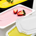 Two containers of pink and yellow ice cream with strawberries on a white background