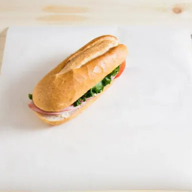 Submarine sandwich with lettuce and tomato on white lunch wrap paper