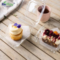 Two small desserts in clear containers on a wooden surface with 'RePlay' branding.