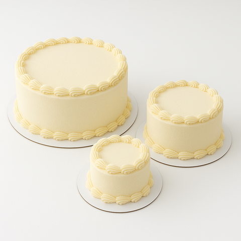 Three round cakes of differing sizes on Paperboard Circle Cake Boards with white frosting on a white background