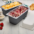 Two ice cream containers with different flavors of ice cream on a light wooden surface with strawberries and waffle cones.